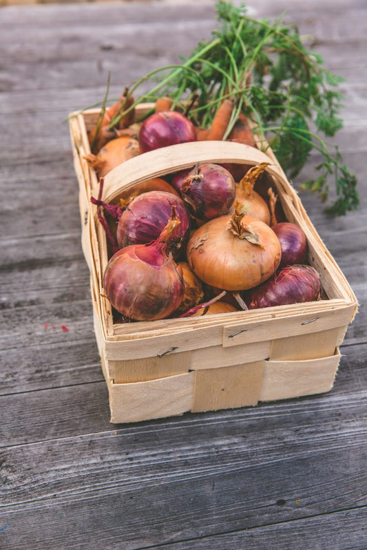 Fresh vegetables including onions arranged on a wooden table, celebrating National Onion Day with Mother Earth Products' favorite onion recipes