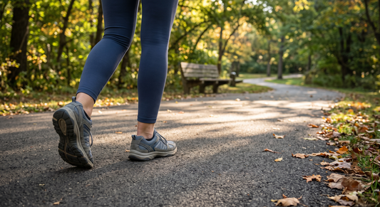 Low rear angle of a pair of walking shoes mid-stride on a dappled park trail